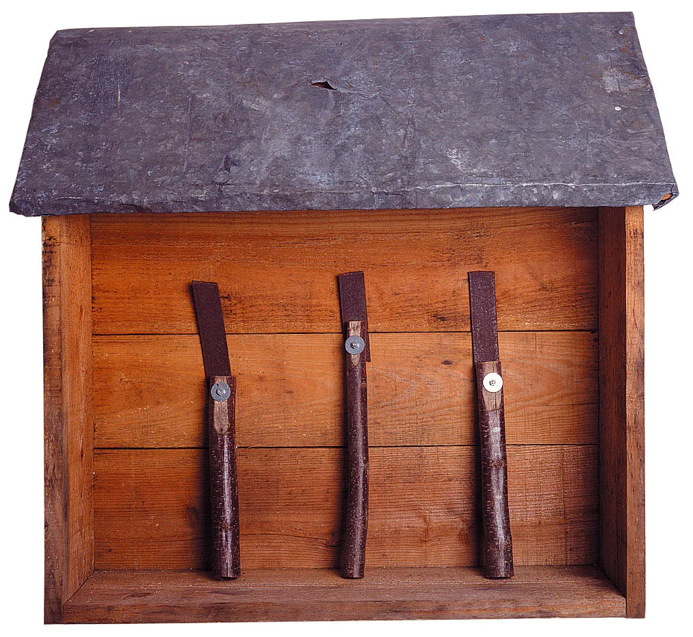 A wooden cabin, hanging on the wall, houses three tools.  Collection: Frac Nouvelle-Aquitaine MÉCA, Bordeaux, inv : 93-365 ©Dominique Fontenat